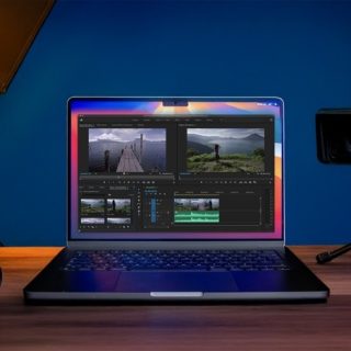 Filmmaker-Approved Tips for Picking the Ultimate Laptop. A laptop displaying video editing software alongside a video camera and a DSLR camera, set in a studio environment.