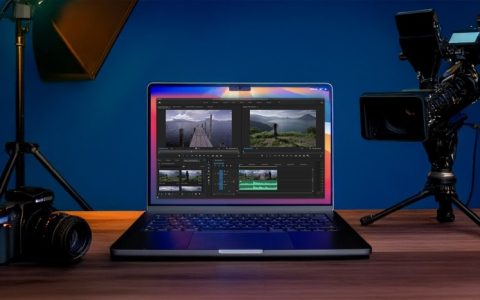 Filmmaker-Approved Tips for Picking the Ultimate Laptop. A laptop displaying video editing software alongside a video camera and a DSLR camera, set in a studio environment.