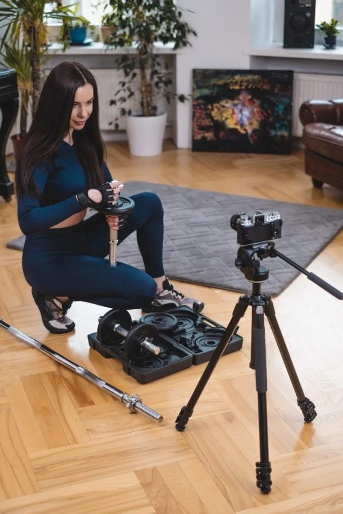 A woman in activewear sets up weights for exercise in a home gym setting