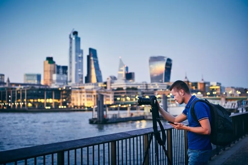 A photographer with a camera is capturing the London skyline at dusk, highlighting the stunning cityscape.