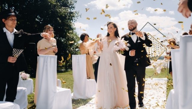 10 Pro Steps for Filmmakers: Cinematic Wedding Videos That Couples Love. A joyful bride and groom celebrate their wedding day surrounded by confetti in a beautiful outdoor setting.