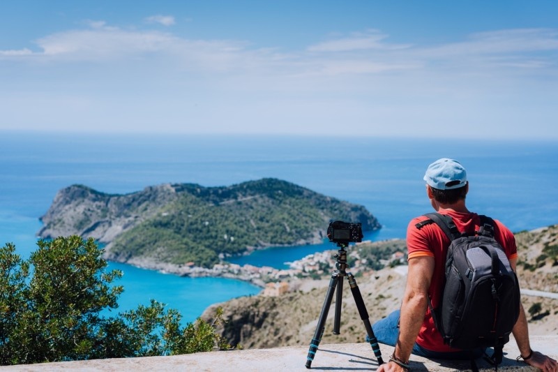 A photographer enjoying a scenic view of the ocean and island from a high vantage point