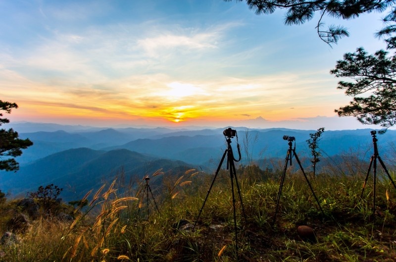 Photographers setting up cameras to capture a stunning mountain sunset with vibrant colors