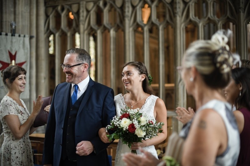 A joyful bride and her companion smiling during a wedding ceremony in a beautiful church setting.