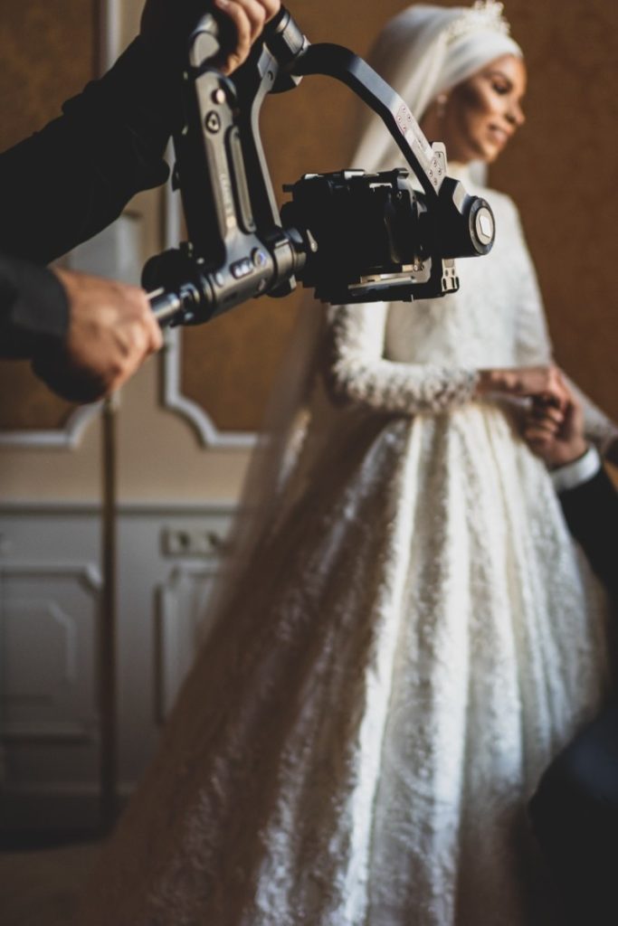 A videographer capturing a beautiful bride in a stunning wedding dress with a camera gimbal, creating a memorable wedding photography scene.