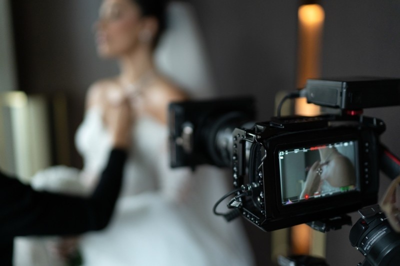 A wedding videographer capturing footage of a bride during preparations, showcasing elegant bridal attire and accessories.