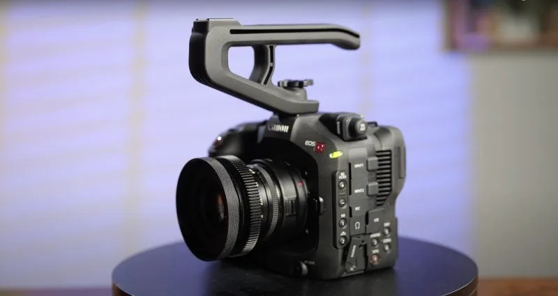 A Canon EOS camera with a large lens positioned on a black surface, highlighted against a softly lit background.