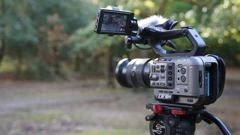 A Sony camera set on a tripod in a natural outdoor setting, showcasing its capabilities for 4K video recording.