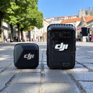 DJI Mic 2 vs Mic Mini: 6-Month Real-World Comparison Review. A DJI wireless microphone system displayed on a cobblestone street, featuring a compact transmitter and receiver.