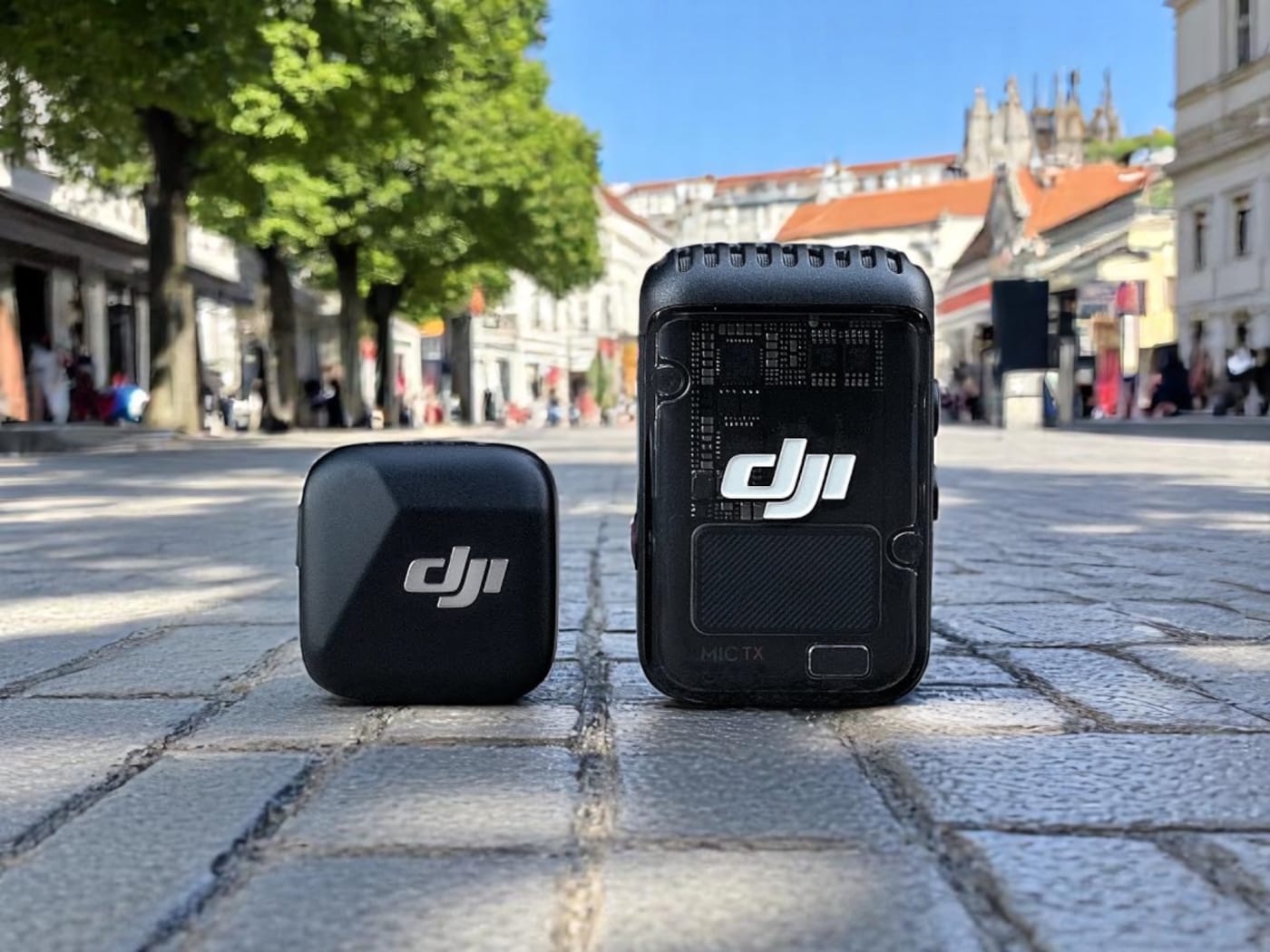 DJI Mic 2 vs Mic Mini: 6-Month Real-World Comparison Review. A DJI wireless microphone system displayed on a cobblestone street, featuring a compact transmitter and receiver.